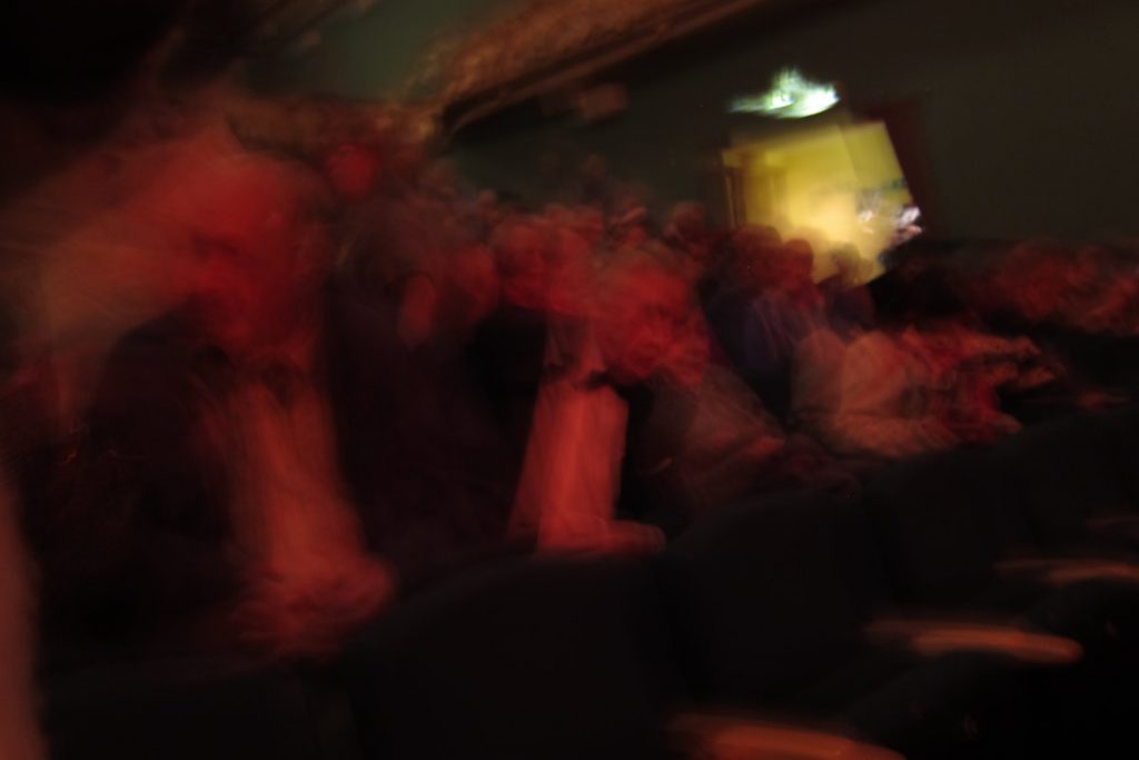 Blurry photo of some well-dressed chatterboxes at a theatre
